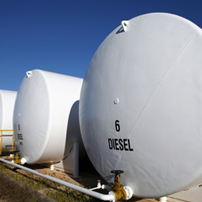 Large white cylindrical storage tanks labeled DIESEL and numbered, positioned outdoors under a clear blue sky, with connected pipes at the base.